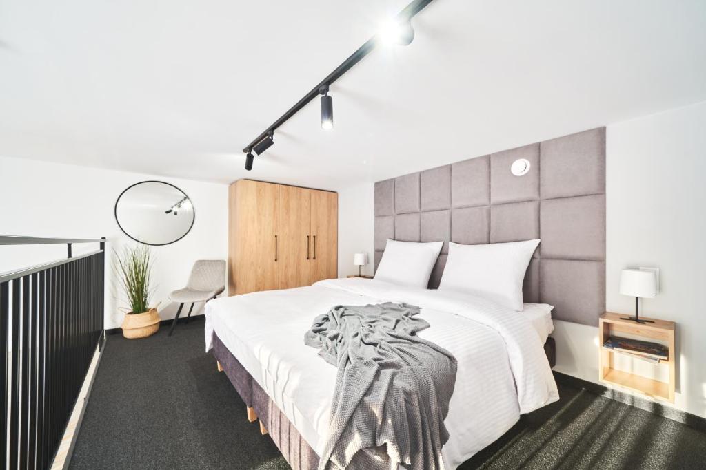 1 dormitorio con 1 cama blanca grande y cabecero grande en Na Fursie Apartments & Rooms, en Nowy Targ