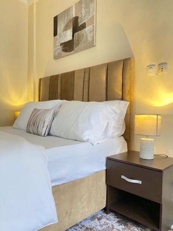 a bed with a wooden headboard next to a table at Armelle Sweet Home in Douala