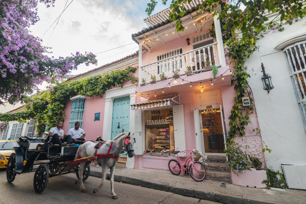 un carruaje tirado por caballos frente a un edificio rosa en CASA HADASA en Cartagena de Indias