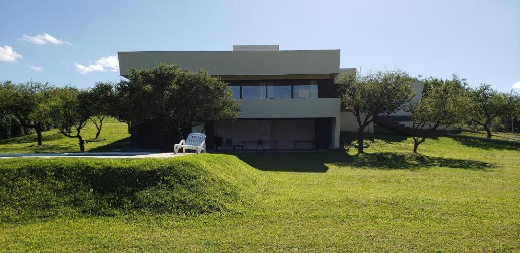 una casa con una silla blanca delante de ella en Casa Carlos Paz en Country Causana en Villa Carlos Paz