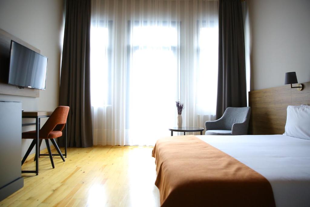 Habitación de hotel con cama, escritorio y TV. en ROCO Beyoglu, en Estambul