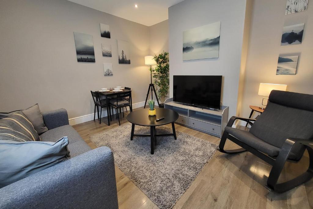 ein Wohnzimmer mit einem Sofa, einem TV und einem Tisch in der Unterkunft Park House Modernised 2 Bedroom Property in Knowsthorpe