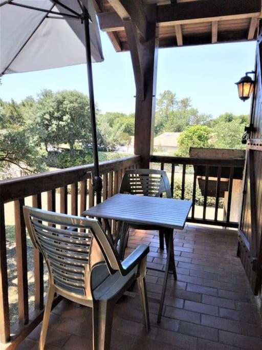 - une table et des chaises sur une terrasse couverte avec un parasol dans l'établissement Papillon, à Lit-et-Mixe
