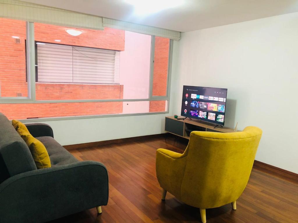 een woonkamer met 2 stoelen en een flatscreen-tv bij Elegante suite amoblada - Park La Carolina cerca Hotel Dann Carlton in Quito