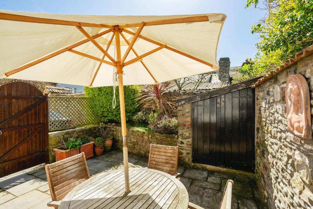 a wooden table with an umbrella on a patio at CROYDE VICTORIA COTTAGE 2 Bedrooms in Croyde