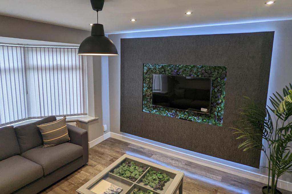 a living room with a couch and a tv on a wall at Modernised 4 Bedroom Property Close To City Centre, Harehills Lane in Roundhay