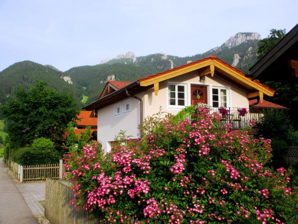 a small house with pink flowers in front of it at Ferienwohnung Schrödel in Aschau im Chiemgau