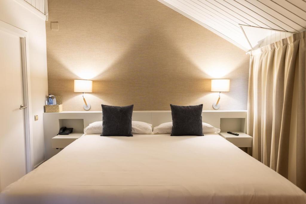 a bedroom with a large white bed with two lamps at Hotel Xalet del Golf in Puigcerdà