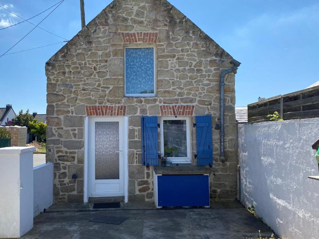 Cette petite maison en pierre possède des portes et des fenêtres bleues. dans l'établissement Charmante maison en pierre à Été, proche mer, plages, sentiers côtiers, idéale pour 2 personnes - FR-1-397-16, à Étel