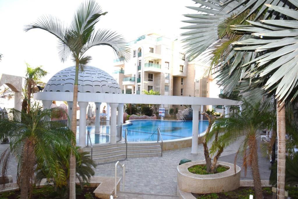 a building with a gazebo and a swimming pool at Sunny 3BR Apartment Golf Residence in Eilat