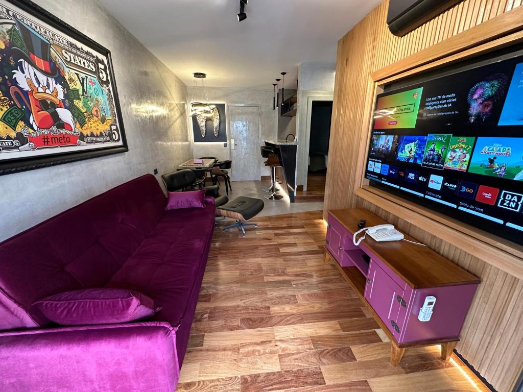 sala de estar con sofá púrpura y TV de pantalla plana en Flat 1092 Jardins, en São Paulo