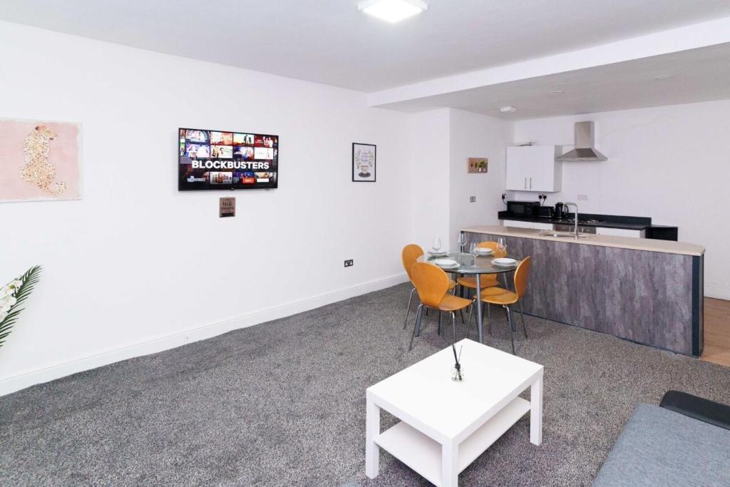 a living room with a table and chairs and a kitchen at Albion High Street Apartments in Leeds