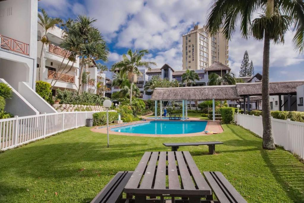 un parc avec un banc et une piscine dans l'établissement 11 La Pirogue Ballito, à Ballito