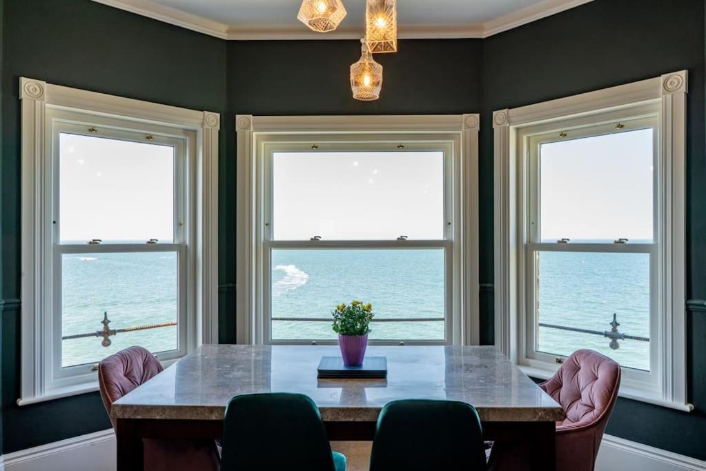 a dining room with a table and three windows at Luxury Duplex Penthouse on the Beach with Panoramic Sea Views in Herne Bay