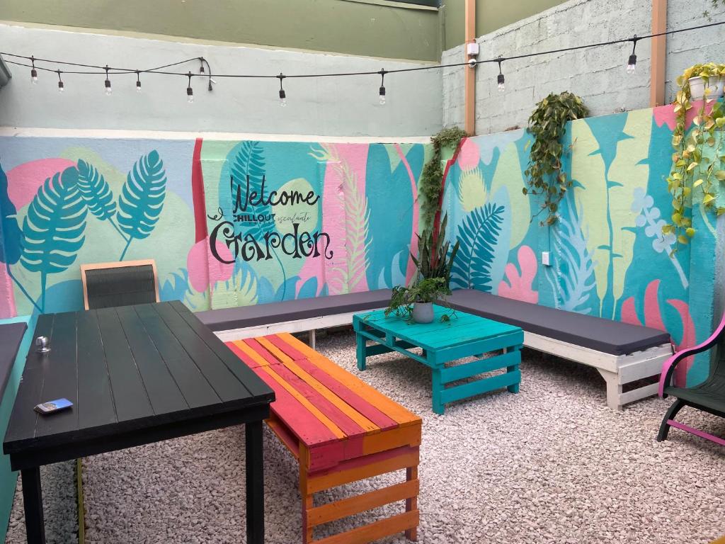 Habitación con bancos y mesas con una pared colorida. en Chillout Hostel Barrio Escalante, en San José