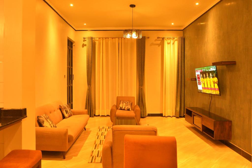 a living room with couches and a flat screen tv at Hilltop apartments in Bwebajja