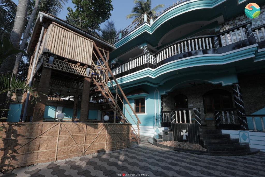 a blue house with a staircase in front of it at Tropical Wave Hostel Morjim Goa in Morjim