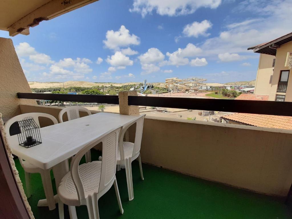 une table blanche et des chaises sur un balcon avec vue dans l'établissement Appartement Rénové Face au Parc Aquatique, Proche Plages et Commerces, Parking Privé - FR-1-239-107, à Seignosse