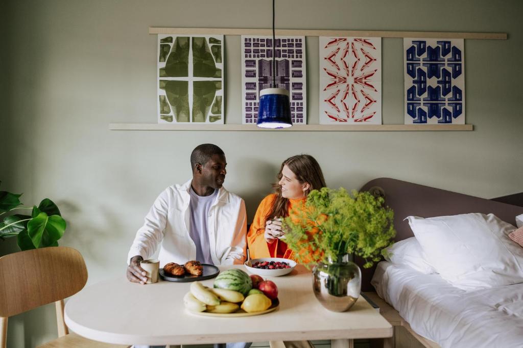 a man and woman sitting at a table with a plate of fruit at Hotel Jansen Amsterdam Bajeskwartier in Amsterdam