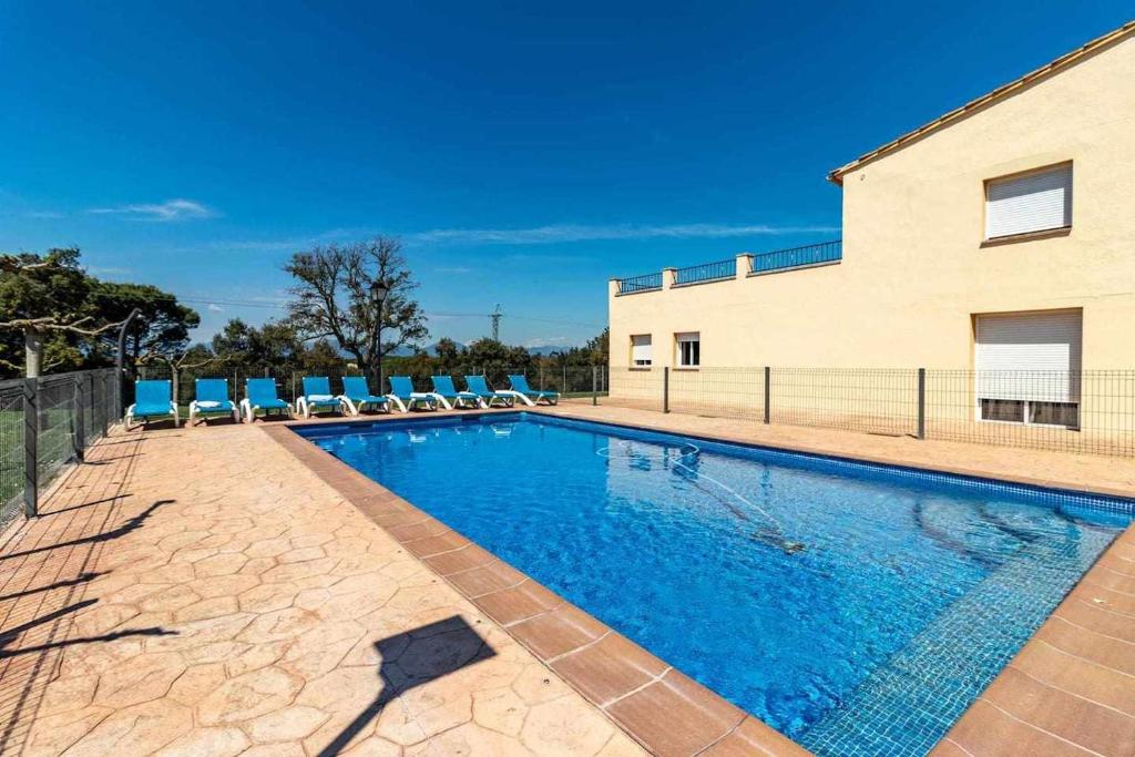 a swimming pool with chairs and a building at Can Bugantó amplia casa con piscina y jardín in Llambillas