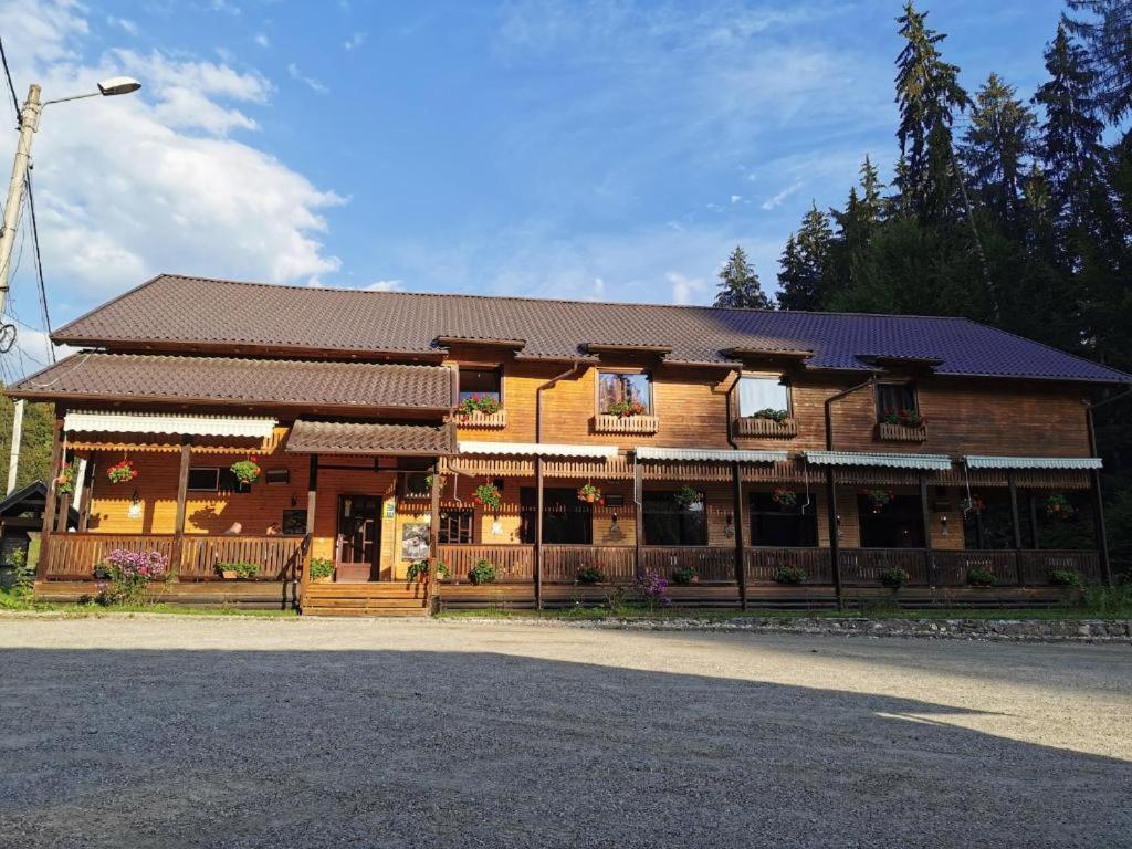 - un grand bâtiment en bois avec une terrasse couverte dans l'établissement Pensiunea Valea Cetatii, à Râșnov