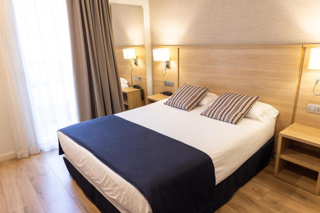 a hotel room with a large bed with two pillows at Hotel Terminus in Puigcerdà