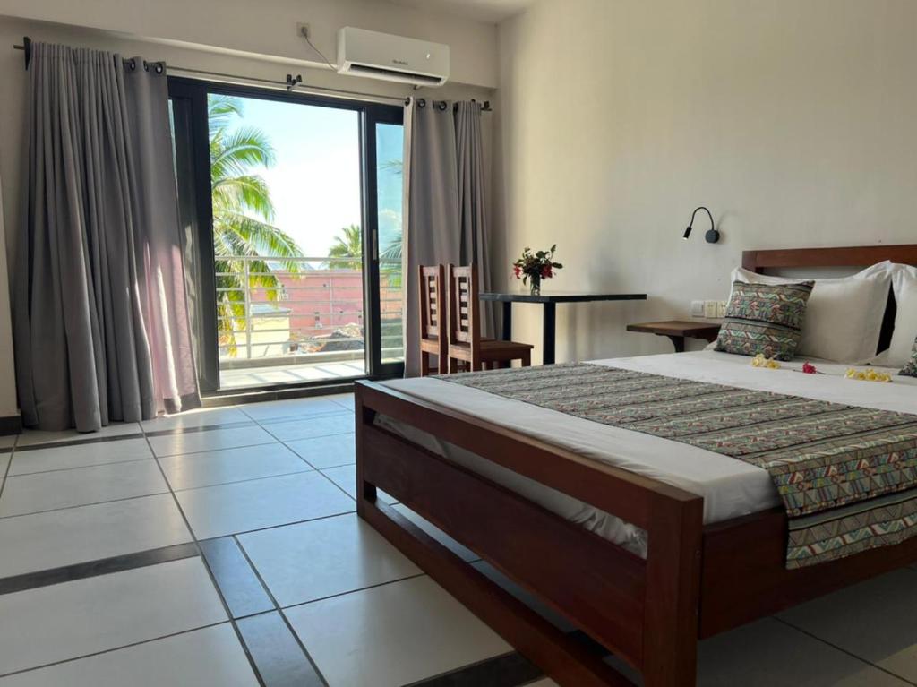 Un dormitorio con una cama grande y una ventana grande. en Hôtel Grand Bay, en Nosy Be