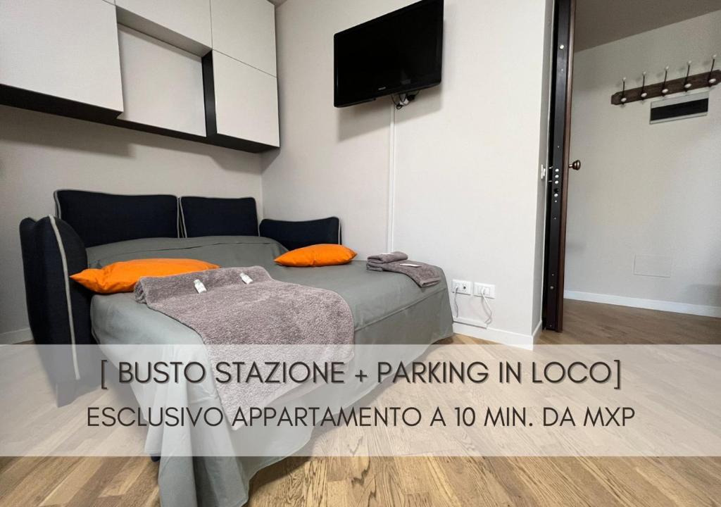 - une chambre avec un lit doté d'oreillers orange et une télévision dans l'établissement Grazioso Appartamento a 10 min da MXP, à Busto Arsizio