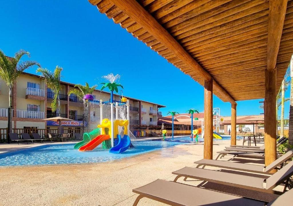 una piscina con un parque infantil con toboganes y sillas en Ondas Praia Resort, en Porto Seguro