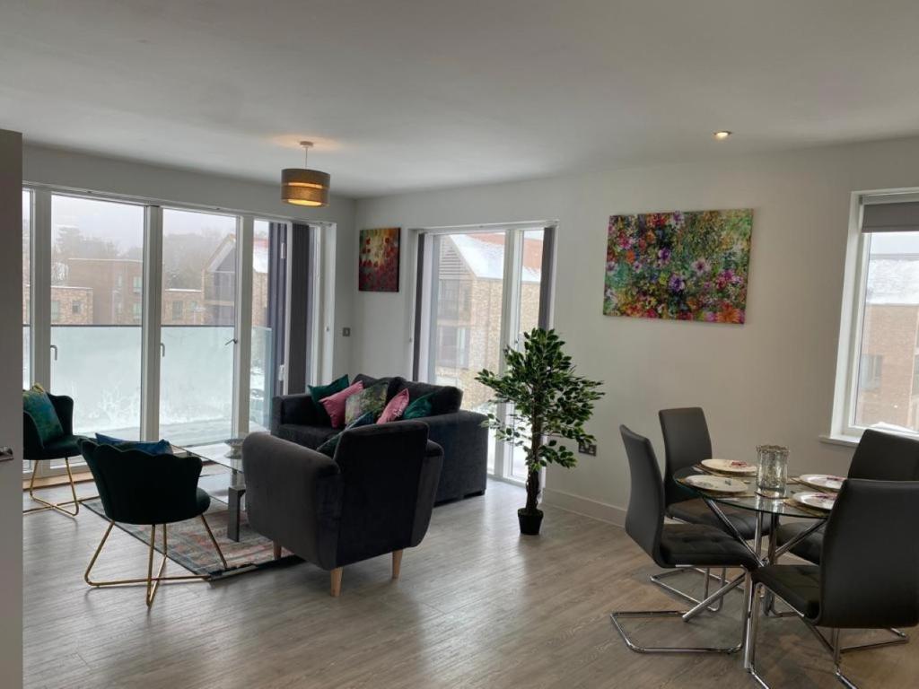 a living room with a couch and a table and chairs at Contemporary & Homely 2 Bed Apartment 10 mins walk to Addenbrookes & Papworth hospitals & Bio Medical Campus in Trumpington