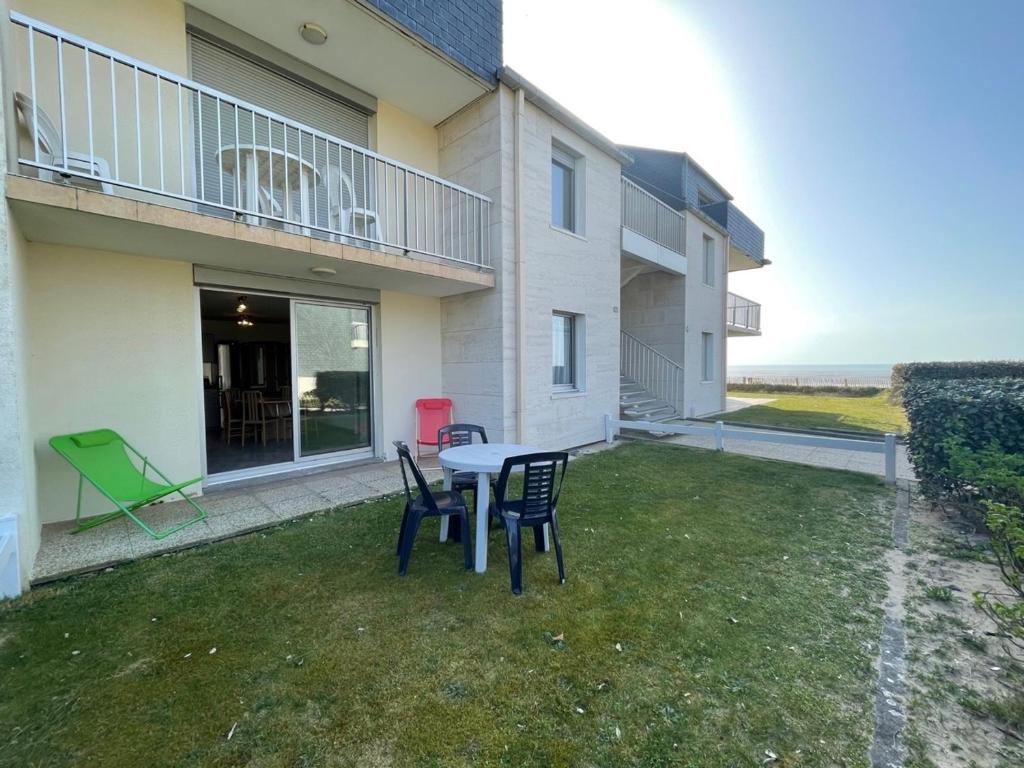 um pátio com uma mesa e cadeiras em frente a um edifício em Appartement Jullouville, 2 pièces, 4 personnes - FR-1-361-14 em Jullouville-les-Pins