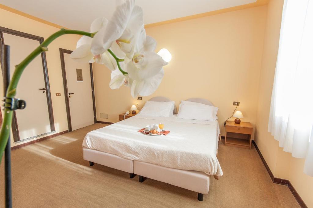- une chambre dotée d'un lit avec des draps blancs et des fleurs dans l'établissement Hotel San Marco, à Bedonia