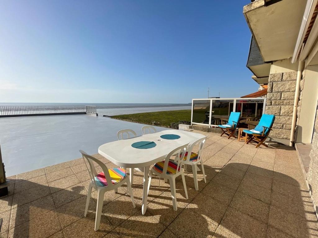 une table et des chaises sur une terrasse avec vue sur l'océan dans l'établissement Appartement en bord de mer avec terrasse et parking - FR-1-361-85, à Jullouville