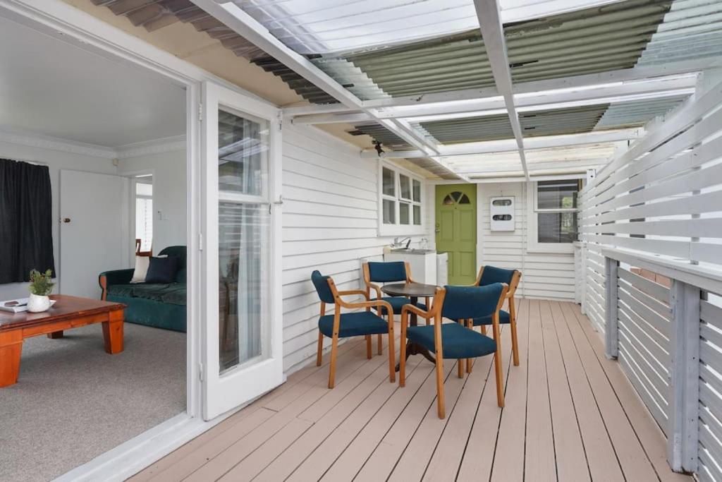 eine Terrasse mit einem Tisch und Stühlen auf einer Terrasse in der Unterkunft Homey Hideaway 3 BR w Parking , Wi-fi and Netflix in Auckland