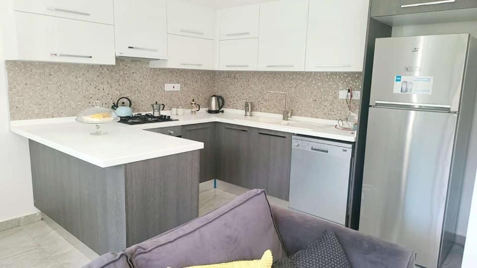 a kitchen with white appliances and a purple couch at Track Apartment in Scala