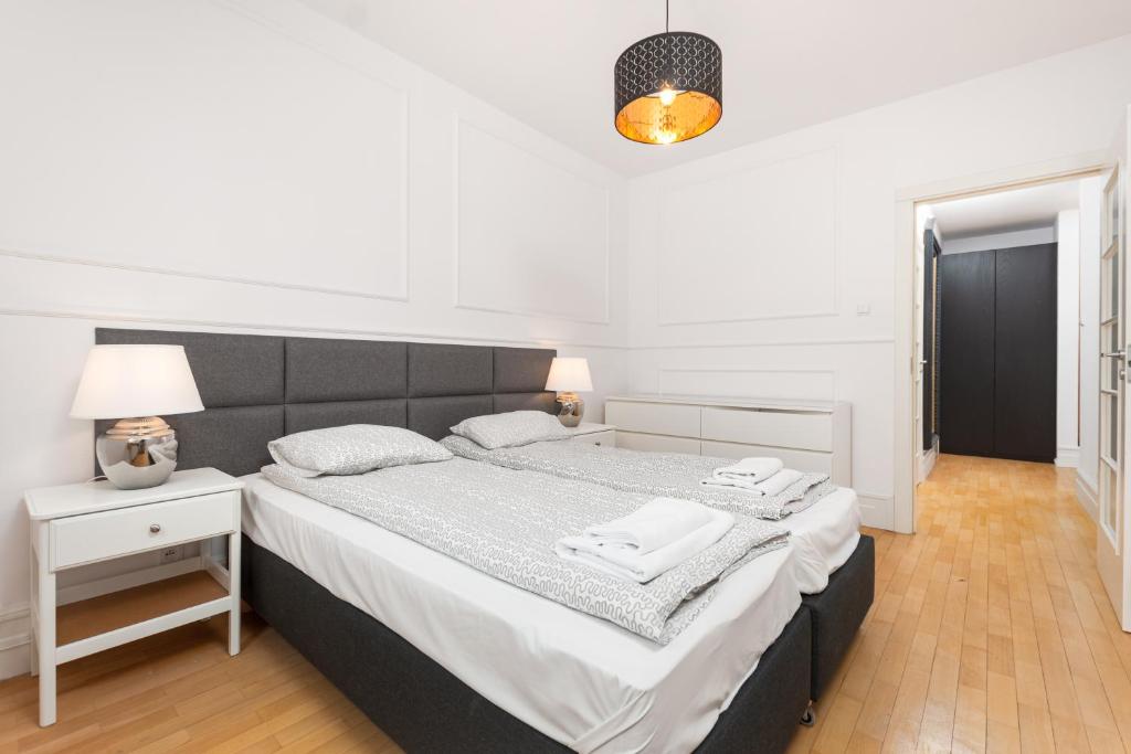 ein weißes Schlafzimmer mit einem großen Bett und einer Lampe in der Unterkunft Apartament Polna by Your Freedom in Warschau