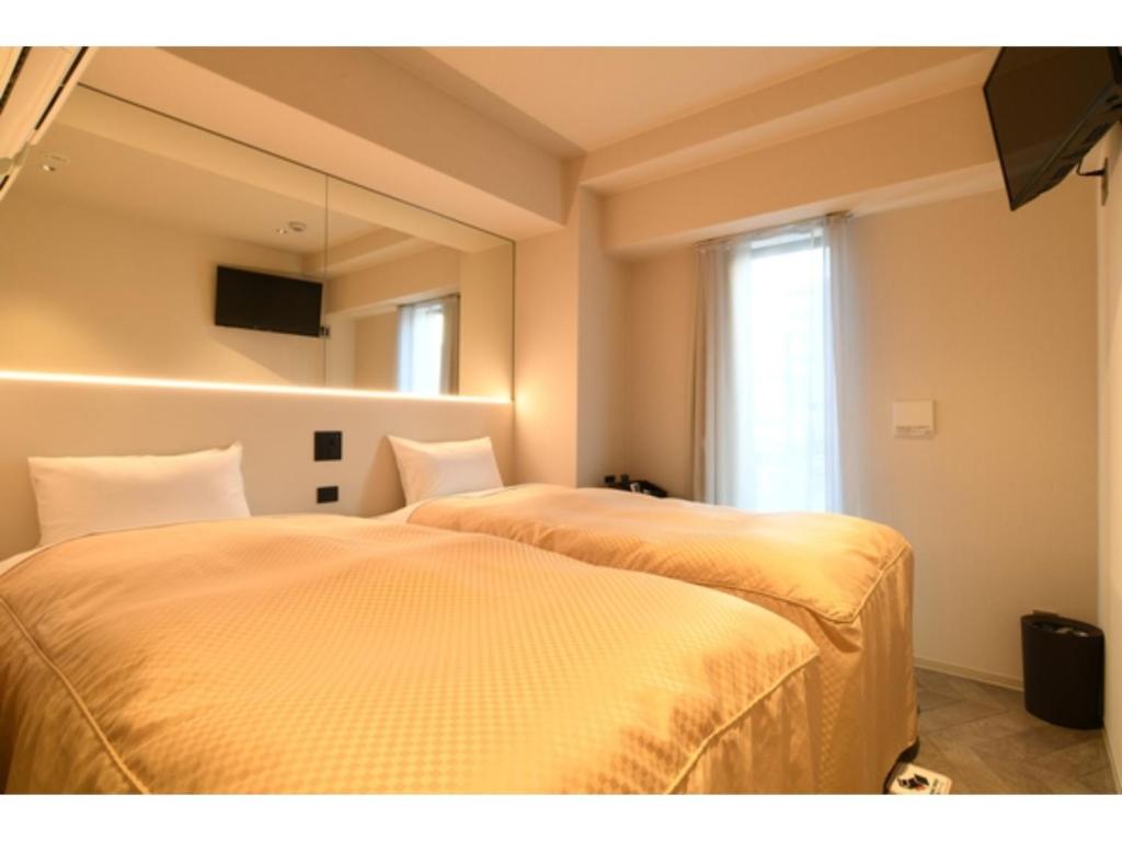 a bedroom with two beds and a mirror and a window at Hotel Wisteria NARA - Vacation STAY 99245v in Nara