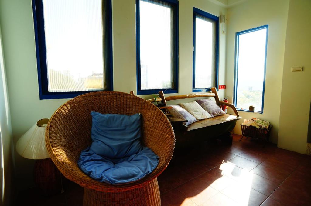 a wicker chair with a blue pillow in a room with windows at Morpheus B&amp;B in Kenting