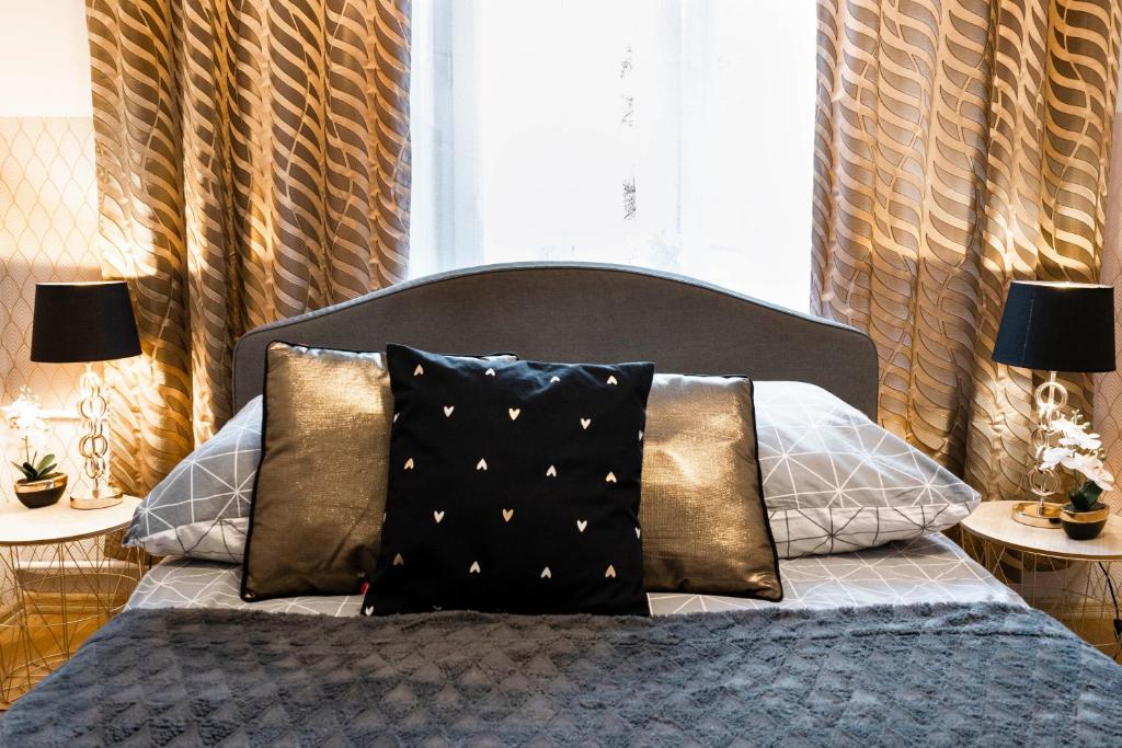 a bed with black and gold pillows in a bedroom at ClickTheFlat Royal Route Warecka Apart Rooms in Warsaw