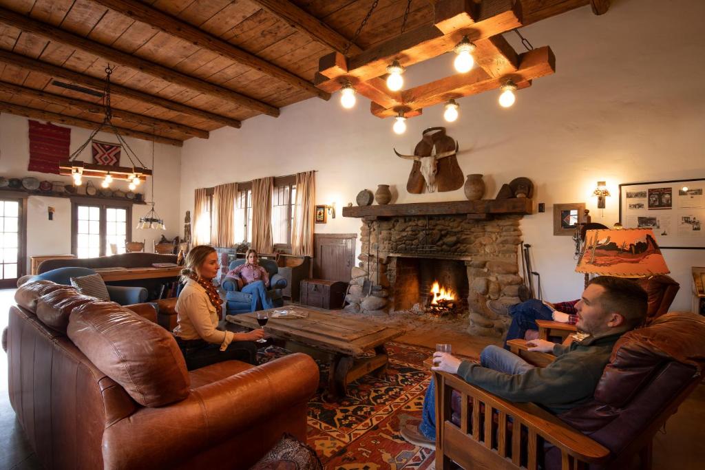a group of people sitting in a living room with a fireplace at Kay El Bar Guest Ranch in Wickenburg