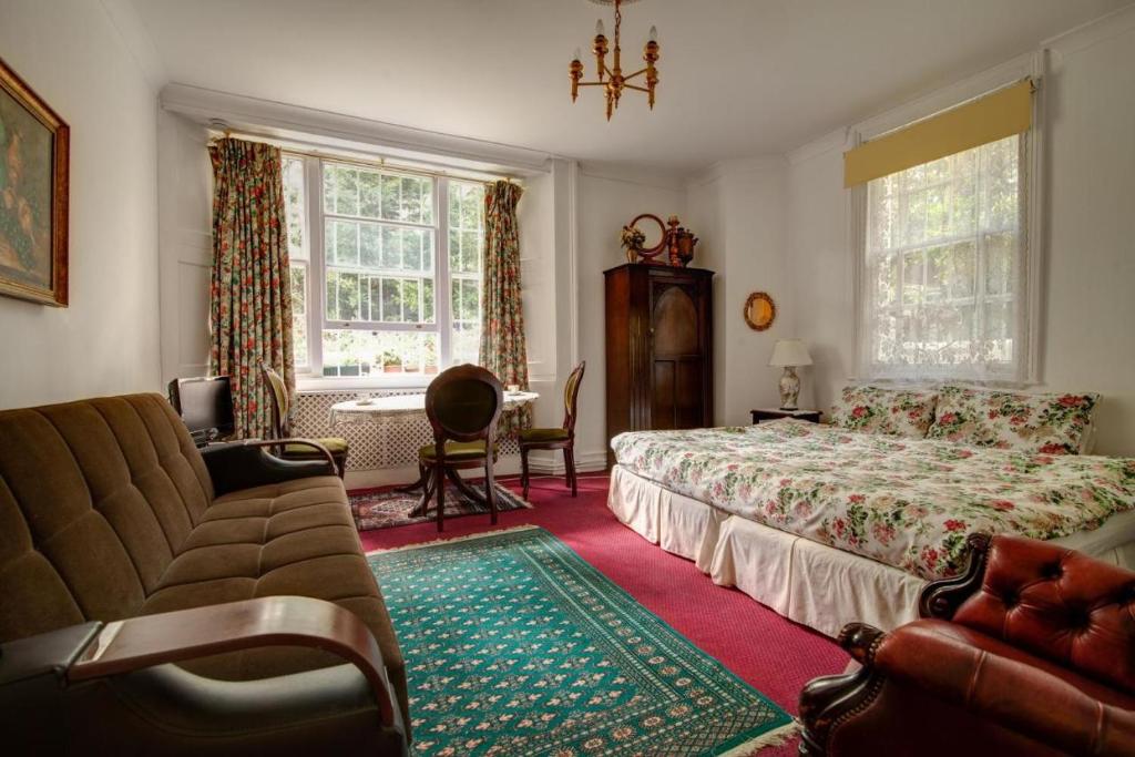 a bedroom with a bed and a couch and a chair at Dawson Place, Juliette's Bed and Breakfast in London