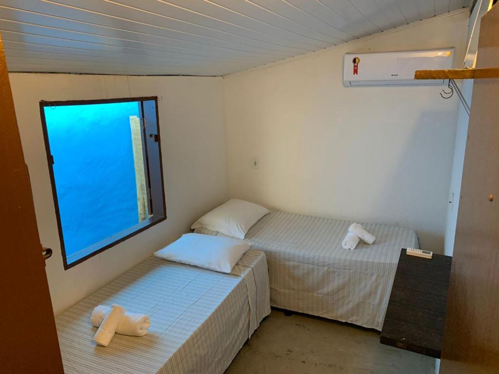 2 camas en una habitación pequeña con ventana en Casa da Lua no centro da Vila de Caraíva ao lado da Igreja de Caraíva, en Caraíva