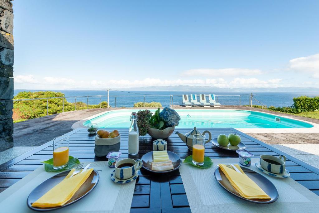 a table with plates of food next to a swimming pool at A Casa do Jaime in Prainha de Baixo