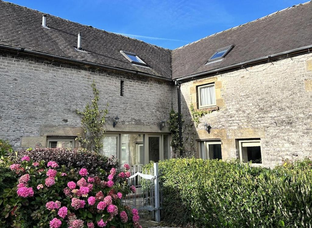 ein Backsteinhaus mit rosa Blumen davor in der Unterkunft Nadin Cottage in Buxton