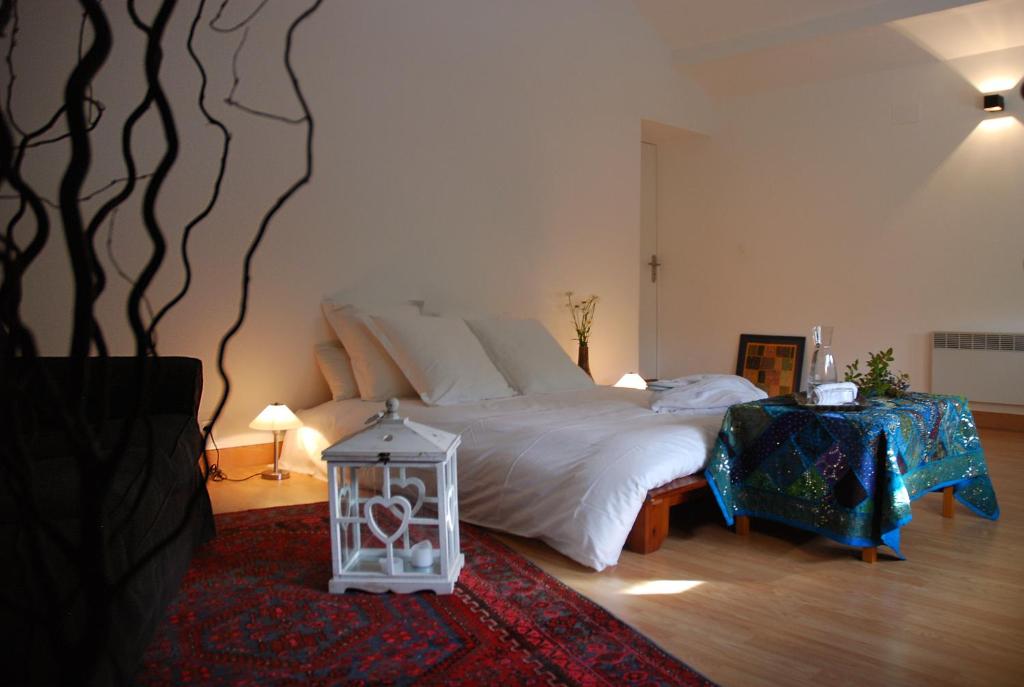 een slaapkamer met een groot bed en een tafel met een lamp bij Le Prana - Les Chambres d'Hôtes, Wellness et Centre de soins in Rozérieulles