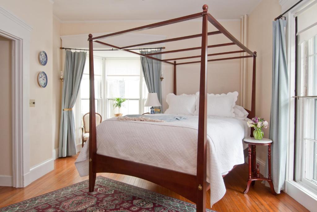 um quarto com uma cama de dossel e almofadas brancas em Marshall Slocum Inn em Newport