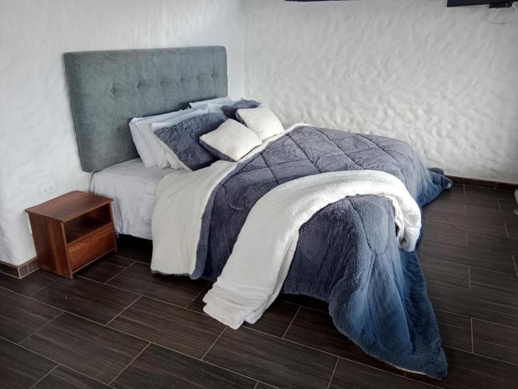 una camera da letto con un letto con una coperta blu e un tavolo di Cabañas camino al cielo a Fúquene