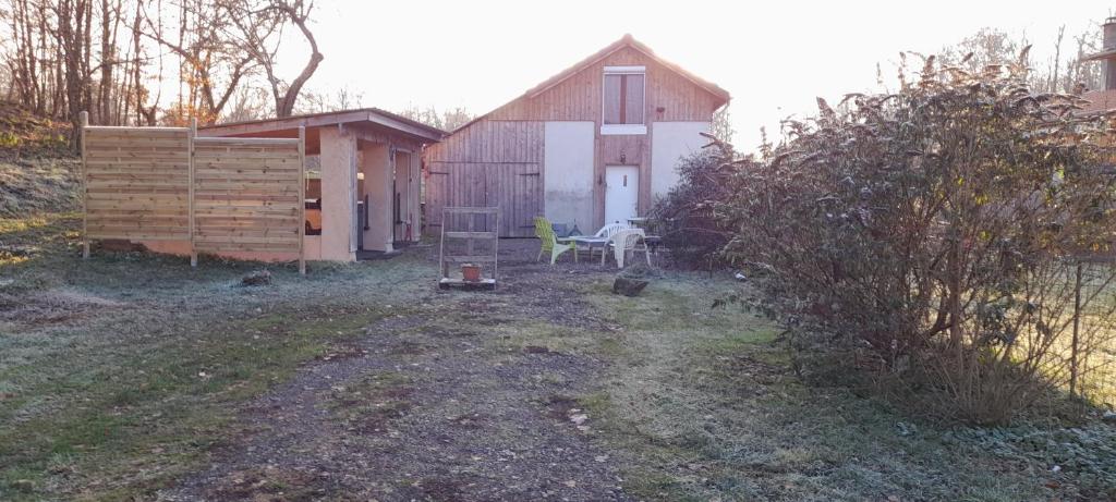 a backyard with a shed and a table and a chair at Gîte de charme avec jacuzzi étang babyfoot et rivière 