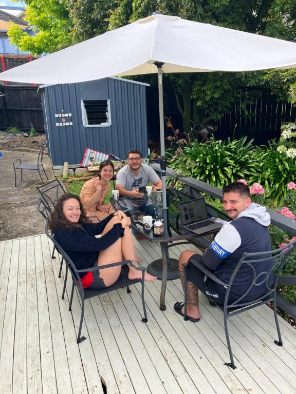 eine Gruppe von Menschen, die auf einem Deck um einen Tisch sitzen in der Unterkunft Kiwi Hosts in Auckland