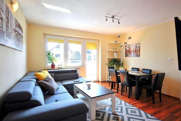 A comfortable apartment with a balcony, very close to the sea, Ustronie Morskie في أوستروني مورسكي: غرفة معيشة مع أريكة زرقاء وطاولة